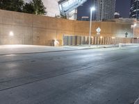 a person is riding on a skateboard down an empty street at night time in the city