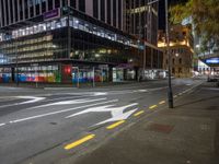 a view of a city street at night with a crosswalk in the foreground