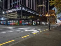 a view of a city street at night with a crosswalk in the foreground