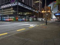 a view of a city street at night with a crosswalk in the foreground