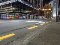 a view of a city street at night with a crosswalk in the foreground