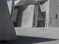 a concrete block with metal strips on it in front of an art museum structure with another building on the other side