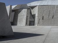 a concrete block with metal strips on it in front of an art museum structure with another building on the other side