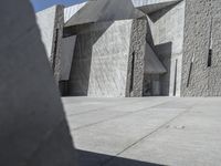 a concrete block with metal strips on it in front of an art museum structure with another building on the other side