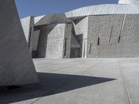 a concrete block with metal strips on it in front of an art museum structure with another building on the other side