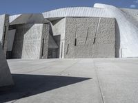 a concrete block with metal strips on it in front of an art museum structure with another building on the other side