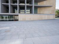 the building is made of concrete and has stone and glass accents, along with a curved staircase