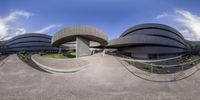 the exterior is made of circular concretes and there are trees on the sidewalk, a fence, and a building