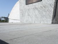 a skateboard is standing on a cement surface next to a building with windows and a view of trees