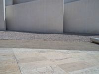 the gray concrete walls of a building have a line of steps on the left side