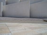 the gray concrete walls of a building have a line of steps on the left side