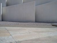 the gray concrete walls of a building have a line of steps on the left side