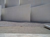 the gray concrete walls of a building have a line of steps on the left side