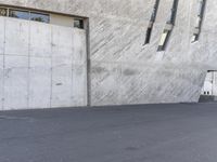 a man on a skateboard in a parking lot and on the street, looking into an area with concrete walls