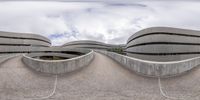 a building that is shaped like a curved bridge with a few cars on the road