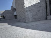 a large, concrete wall with a camera on top and some people walking by next to it