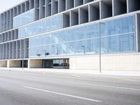 a large building with many windows is on the corner of the street near a highway