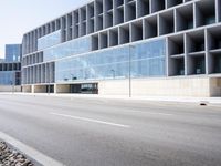 a large building with many windows is on the corner of the street near a highway