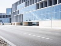 a large building with many windows is on the corner of the street near a highway