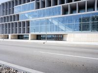 a large building with many windows is on the corner of the street near a highway