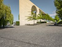 some stone paved street with trees and a building in the background of the image is near a sidewalk