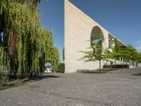 some stone paved street with trees and a building in the background of the image is near a sidewalk