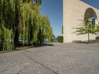 some stone paved street with trees and a building in the background of the image is near a sidewalk