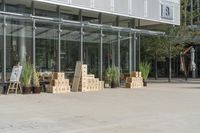 a store front with large windows, plants and cardboard boxes stacked on the floor outside