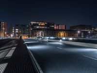 a city street with several cars and an overpass in the distance at night on a bridge