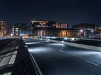 a city street with several cars and an overpass in the distance at night on a bridge