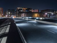 a city street with several cars and an overpass in the distance at night on a bridge