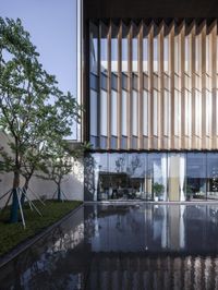 an outside shot of a building with tall windows and reflections in the water nearby is a large mirror