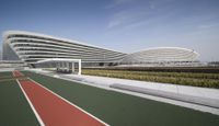 the tennis court is green and red in front of the building has a curved walkway leading to it