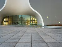 an open area with some lights reflecting off of the side of the building and on the ground