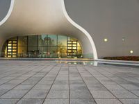an open area with some lights reflecting off of the side of the building and on the ground