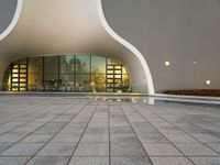 an open area with some lights reflecting off of the side of the building and on the ground