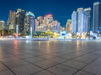 a city view at dusk looking toward a park with fountains and buildings in the background