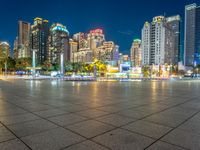 a city view at dusk looking toward a park with fountains and buildings in the background