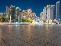 a city view at dusk looking toward a park with fountains and buildings in the background