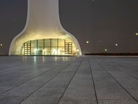 the large, white structure has an arch shaped door on the side of it, lighted up by yellow lamps