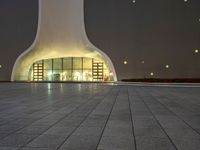 the large, white structure has an arch shaped door on the side of it, lighted up by yellow lamps