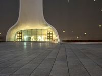 the large, white structure has an arch shaped door on the side of it, lighted up by yellow lamps