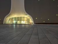 the large, white structure has an arch shaped door on the side of it, lighted up by yellow lamps