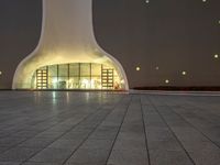 the large, white structure has an arch shaped door on the side of it, lighted up by yellow lamps