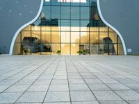 a building with a long glass door that leads to another building, which has stairs, and large windows