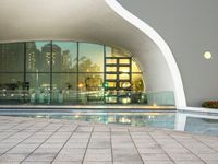 the exterior of a building with large windows reflecting a fountain in it on a walkway