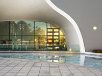 the exterior of a building with large windows reflecting a fountain in it on a walkway