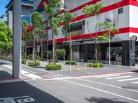 the tree lined streets around a tall building are lined with trees and plants, along with bright red accents