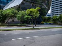 a van parked on the side of a road next to tall buildings and trees in a city