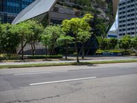 a van parked on the side of a road next to tall buildings and trees in a city